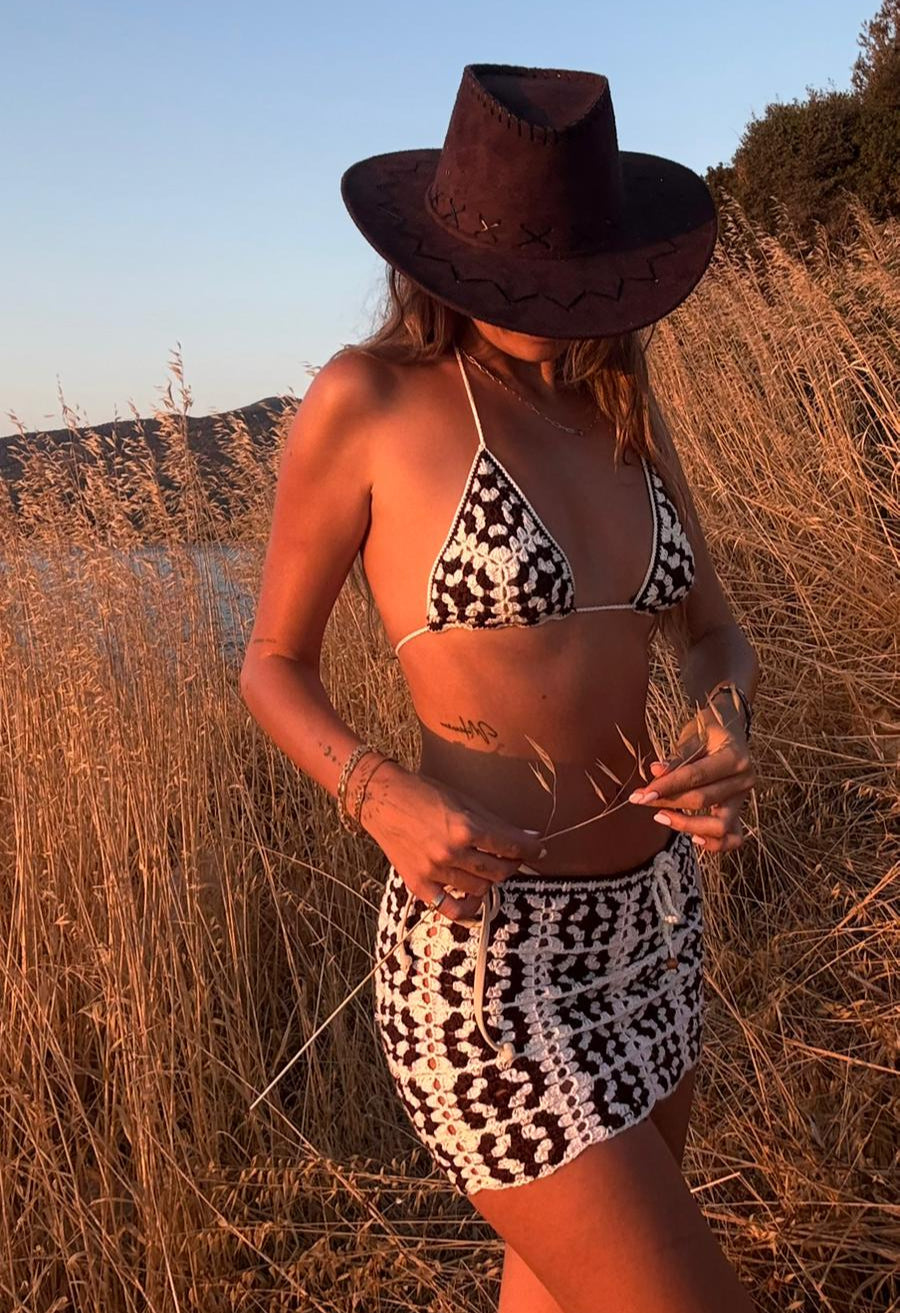 Crochet co-ord set featuring black and white patterned bikini top and skirt, designed as resortwear for beach-to-party looks.